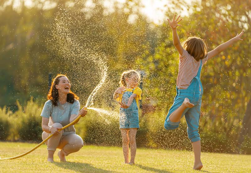 mother cooling off hot kids with garden hose