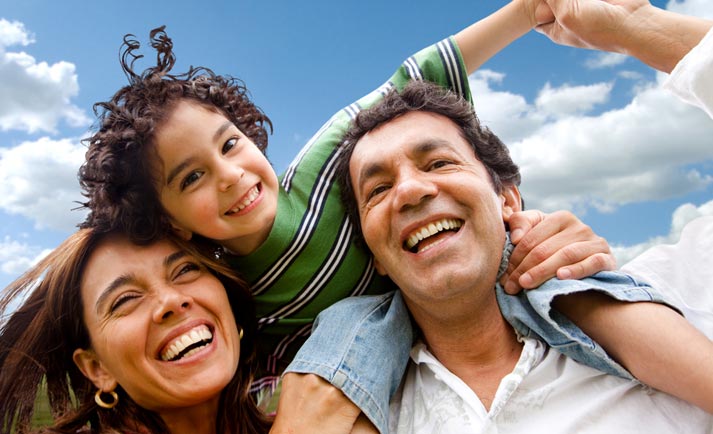 mother, father and happy child riding on parents shoulders