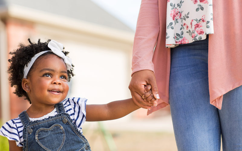 mother lovingly holding hand of little smiling girl