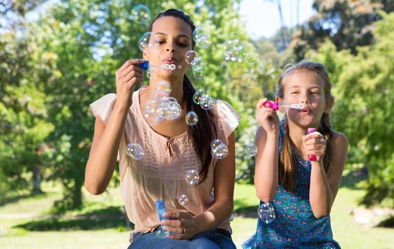 mother with her young daughter blowing bubbles