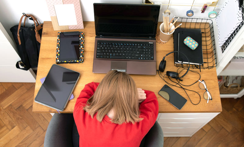 overwhelmed young woman trying to do work from home on her laptop