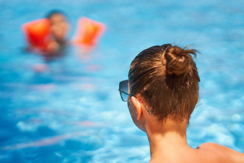 parent on lifeguard duty watching young child in pool