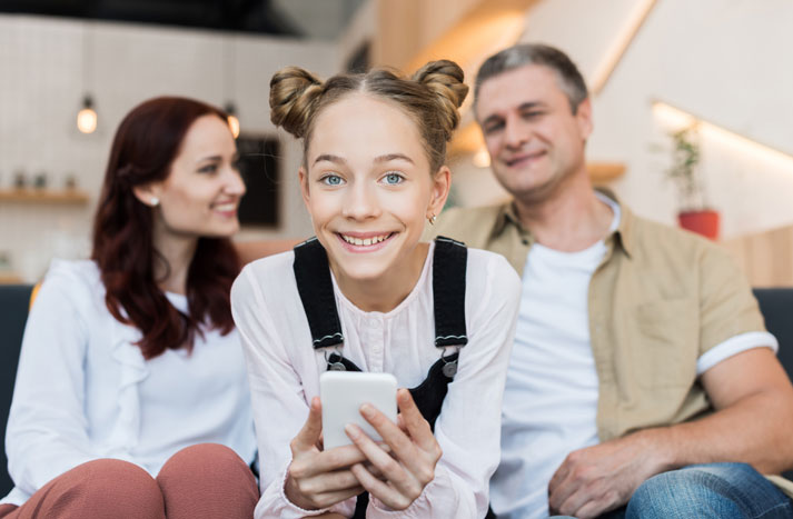 parents chatting while teen daughter is using her phone