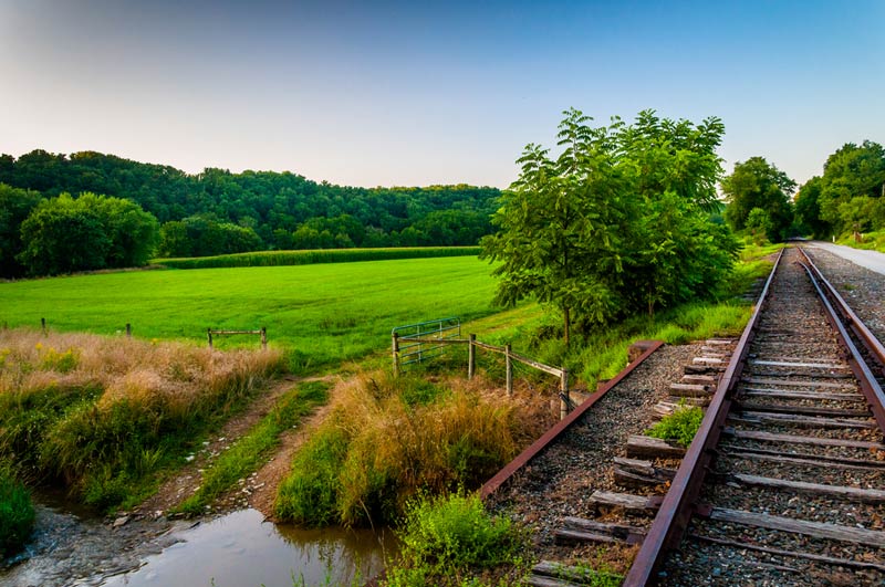 railroad track and road going by farmland