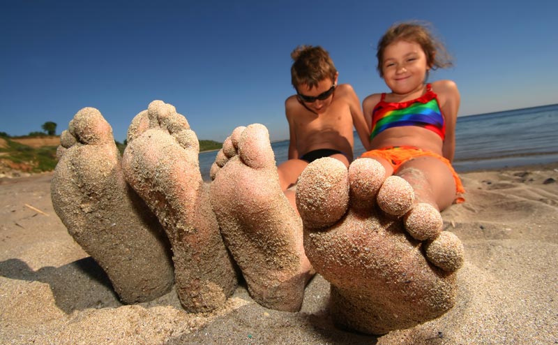 sand covering two siblings feet at the ocean beach