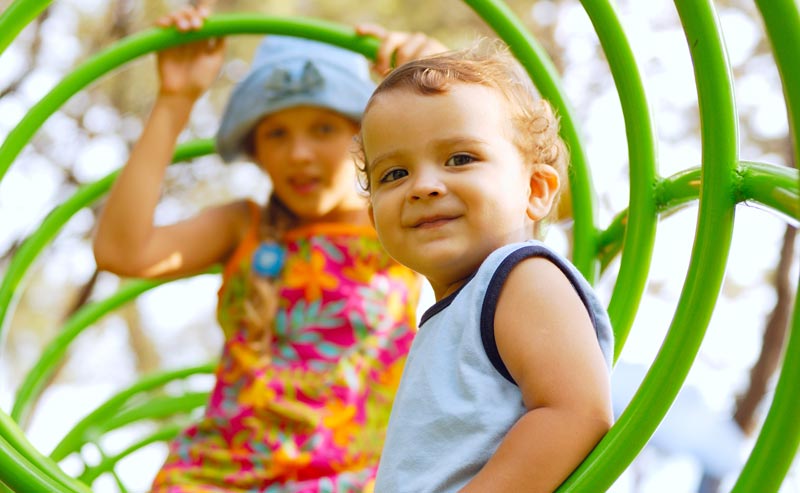 sister and little brother climbing in the playground