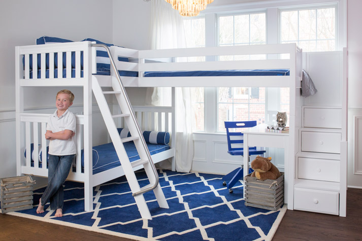 smiling boy beside his three bunk corner Maxtrix bed system