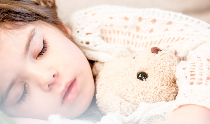 soundly sleeping child hugging teddy bear