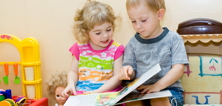 toddler boy and girl reading a book