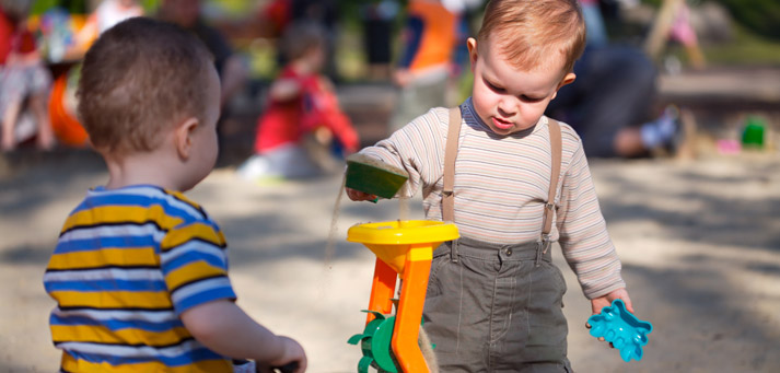 toddlers playing in large sandbox