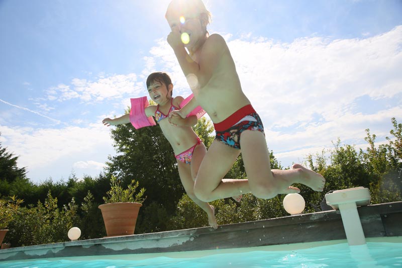 two children jumping into a pool