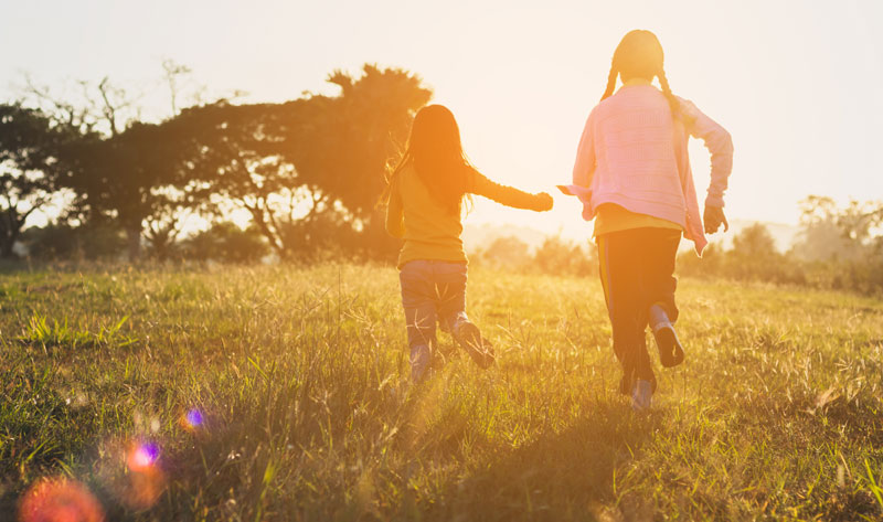 two kids playing outside as sun is setting