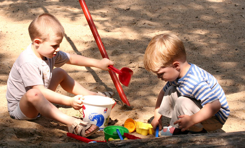two young boys playing in the sand