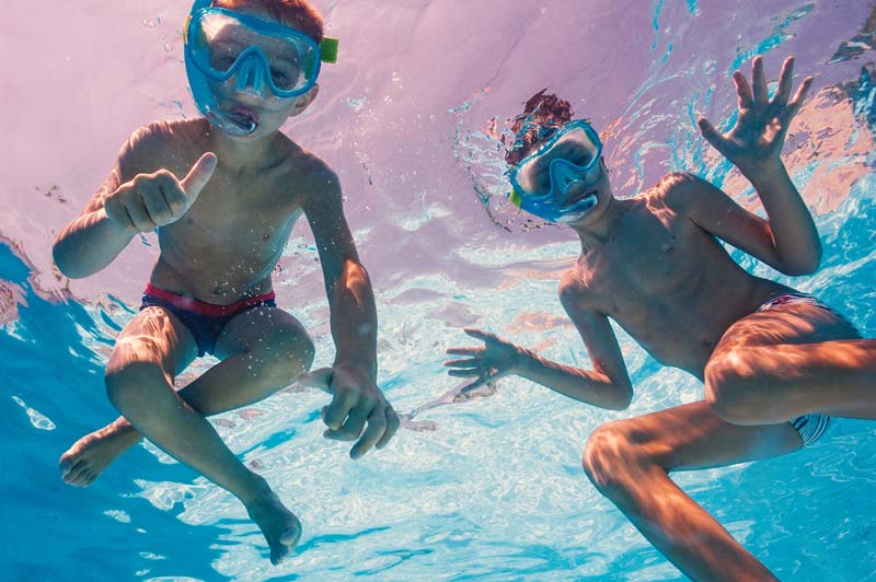 two young brothers swimming with goggles on their faces underwater