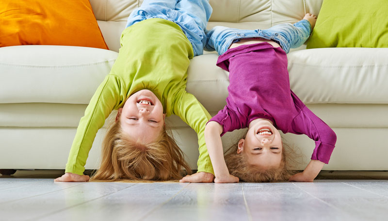 two young girls being silly upside down on couch