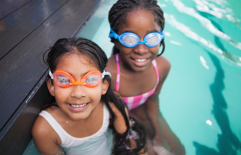 two young girls in pool with goggles on