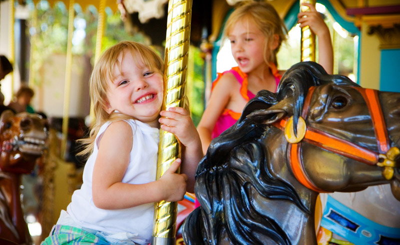 two young girls riding carousel horses