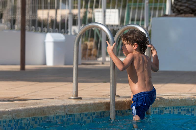 young boy climbing ladder to exit swimming pool