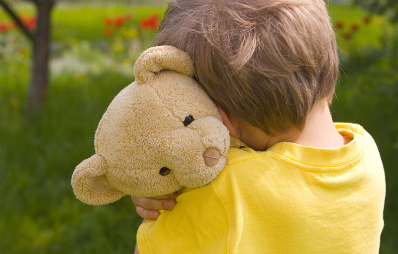 young boy hugging his stuffed teddy bear