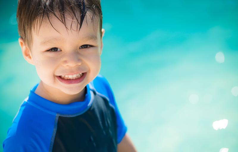 young boy in the water wearing a swim shirt to protect from the sun