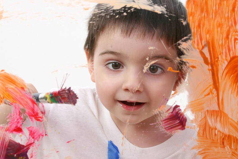 young boy painting colors on glass