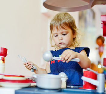 young child playing with toy kitchen