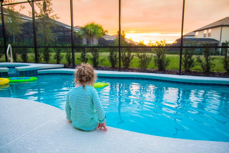 young child sitting alone with her feet in indoor pool water