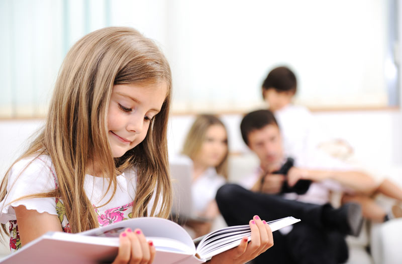 young girl immersed in large book that she is reading