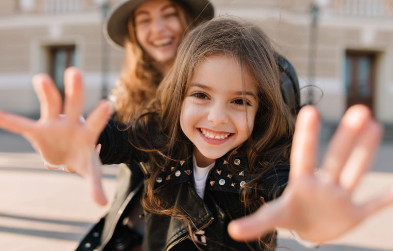 young girl making silly hands toward the camera