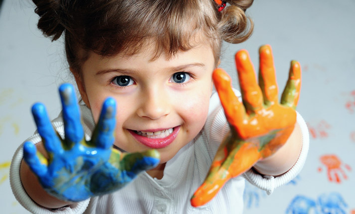 young girl with wet blue and orange paint on her hands