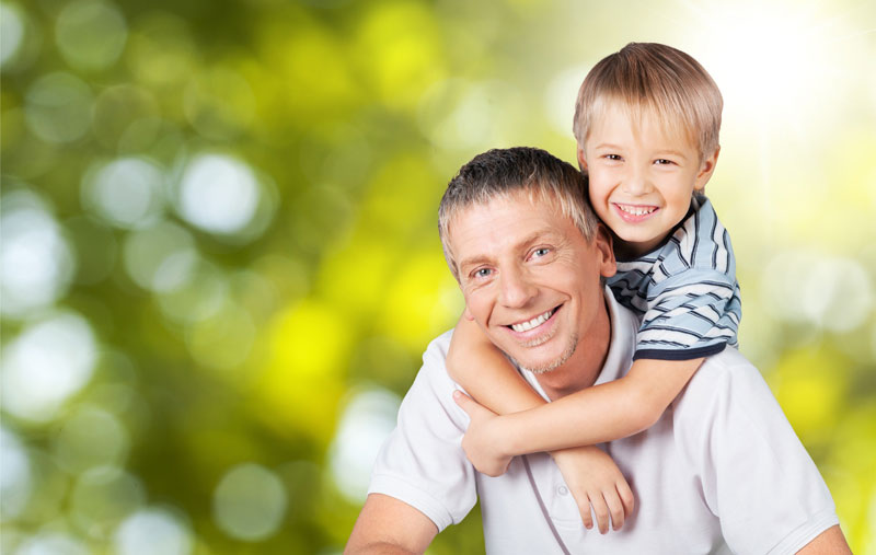 young happy boy riding on dads shoulders